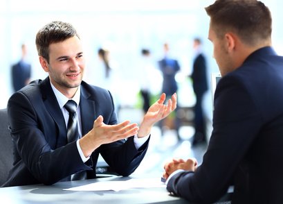 Dos hombres de negocios uno frente al otro en un escritorio en una situación de entrevista