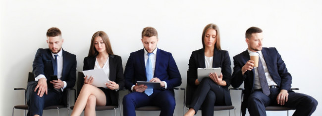 Cinco candidatos de trabajo esperando en recepción para una entrevista